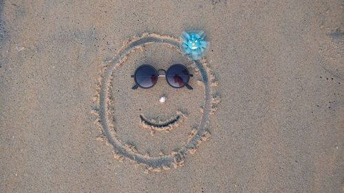 A decorated face drawn using sun glass and shell on the beach