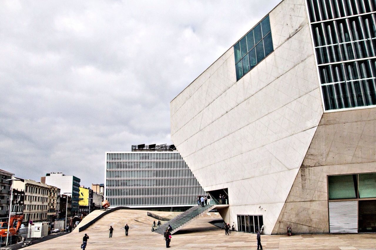 building exterior, architecture, built structure, city, modern, city life, men, sky, office building, building, walking, lifestyles, skyscraper, street, cloud - sky, person, leisure activity, day, large group of people