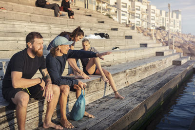 Female and male friends spending leisure time while sitting on steps