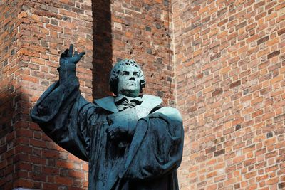 Low angle view of statue against brick wall