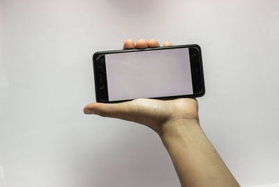 Midsection of person holding smart phone against white background