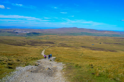 Scenic view of people walking on land against sky