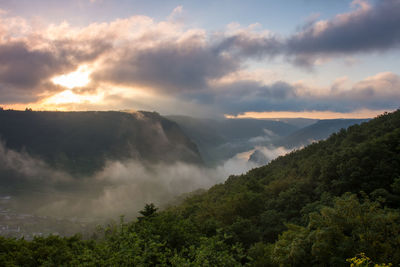 Scenic view of mountains and trees against sky in foggy weather
