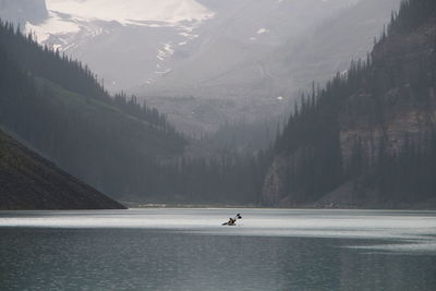 Kayaking across lake louise highlighting the vast water and dramatic landscape.