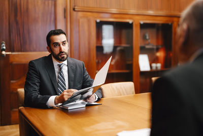 Confident male financial advisor discussing contract with senior businessman in board room