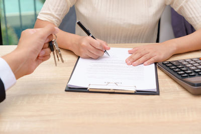 Midsection of woman holding paper with text on table
