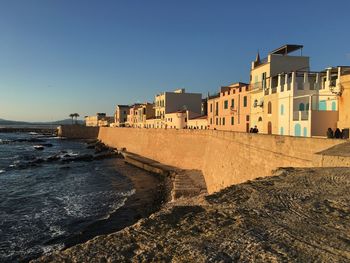 Buildings by sea against clear sky