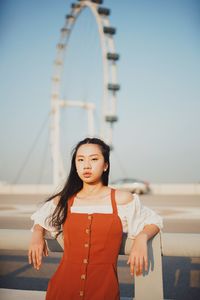 Portrait of woman standing against ferris wheel