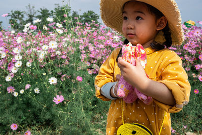 Low angle view of girl standing by flowering plants