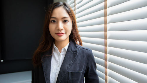 Portrait of young businesswoman standing against wall