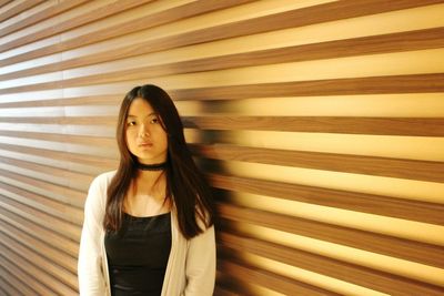 Portrait of young woman standing by wall