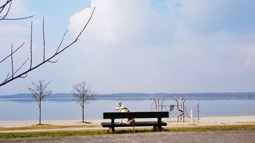 Men sitting at beach against sky