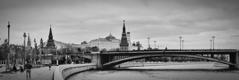 Bridge over river in city against cloudy sky