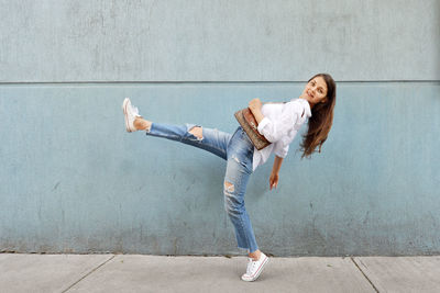 Portrait of young woman looking away against wall