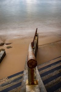 High angle view of rusty railing at beach against sky