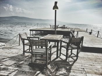 Chairs and table on beach against sky