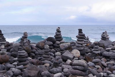 Stack of stones on beach against sky