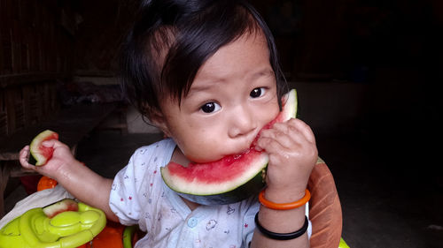 Portrait of cute toddler eating fruit at home