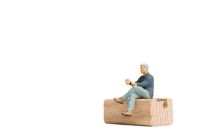 Full length of man sitting on wood against white background