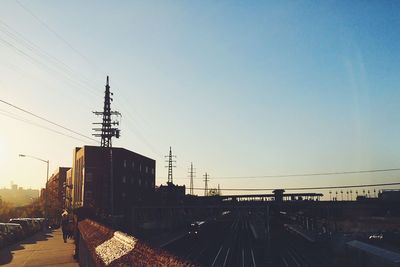 Railroad tracks by buildings against clear sky