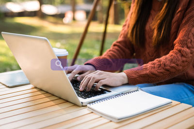 Midsection of woman using laptop at table