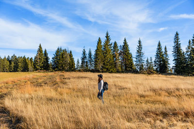 Young woman hiking through a field of golden tall grass.