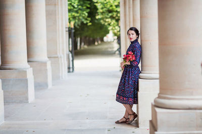 Portrait of elegant woman in a blue dress posing next to a city building