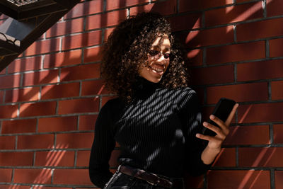 Happy girl with beautiful smile and curly hair using mobile phone