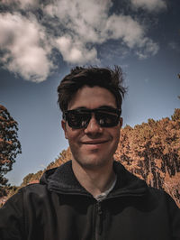 Portrait of young man wearing sunglasses against sky