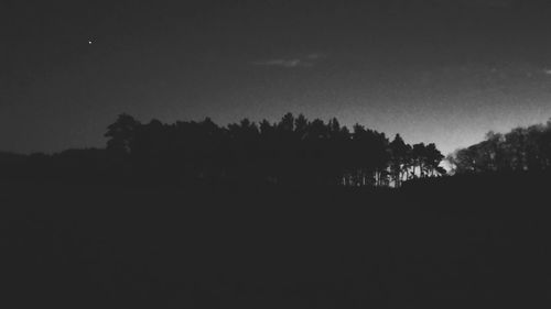 Silhouette trees on field against sky