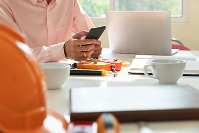 Midsection of man using smart phone in office