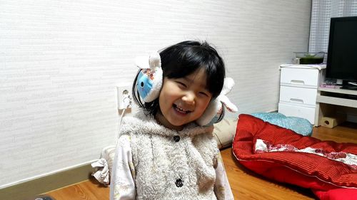 Portrait of smiling girl wearing ear muff at home