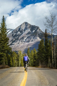 Rear view of man riding bicycle on mountain road