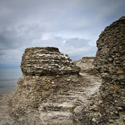 Rock formation on sea shore against sky
