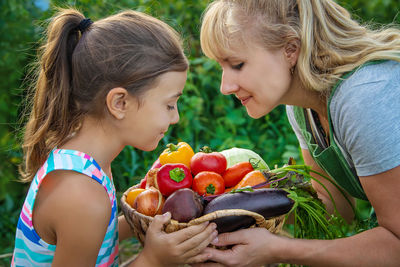 Smiling mother giving vegetables to daughter