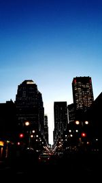 Illuminated buildings against clear sky at dusk