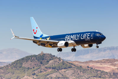 Airplane flying over mountains against clear blue sky