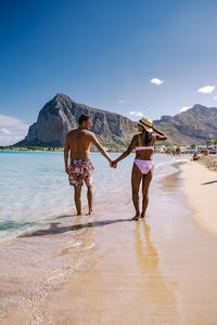 Rear view of woman on beach against sky