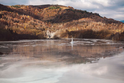 Scenic view of lake by mountain against sky