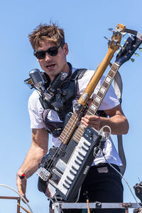 Low angle view of man playing guitar against clear sky