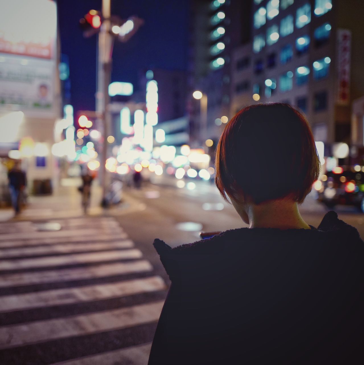 rear view, real people, illuminated, city, technology, wireless technology, men, women, city life, communication, defocused, night, outdoors, people, one person, human body part, cultures, adult, adults only