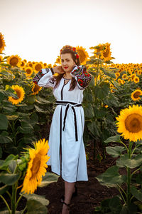 Portrait of young woman standing against yellow flowers
