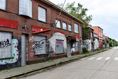 Graffiti on building by street against sky