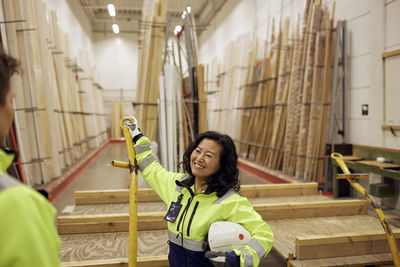 Smiling blue-collar worker discussing with colleague in lumber industry