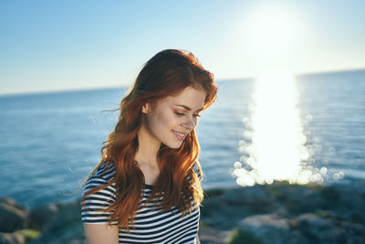 Young woman standing by sea against sky