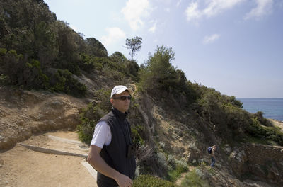 Man standing on dirt road at cliff against sky