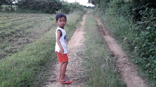 Thoughtful boy looking away while standing on agricultural field