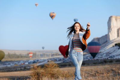 Rear view of young woman with balloons on beach