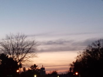 Silhouette of bare trees against sky at sunset