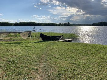 Boat moored on shore by lake against sky